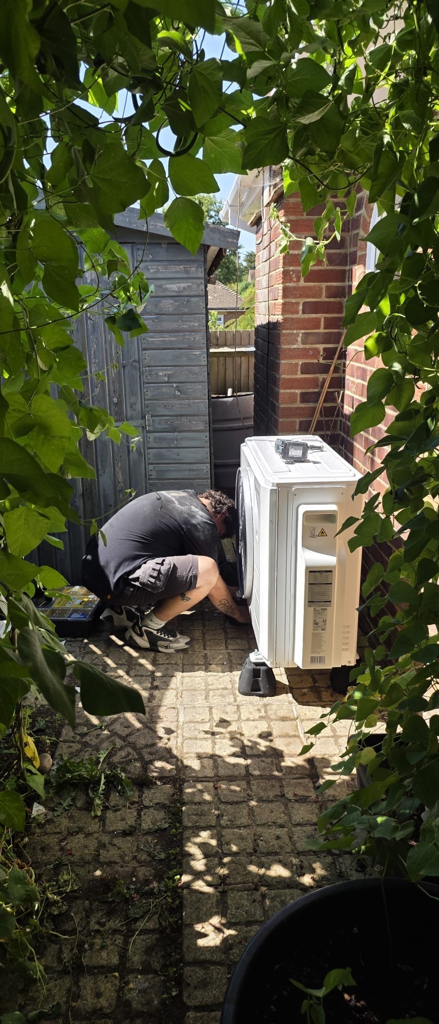 Outdoor condensing unit being installed on anti-vibration feet at a bungalow in Hurstpierpoint